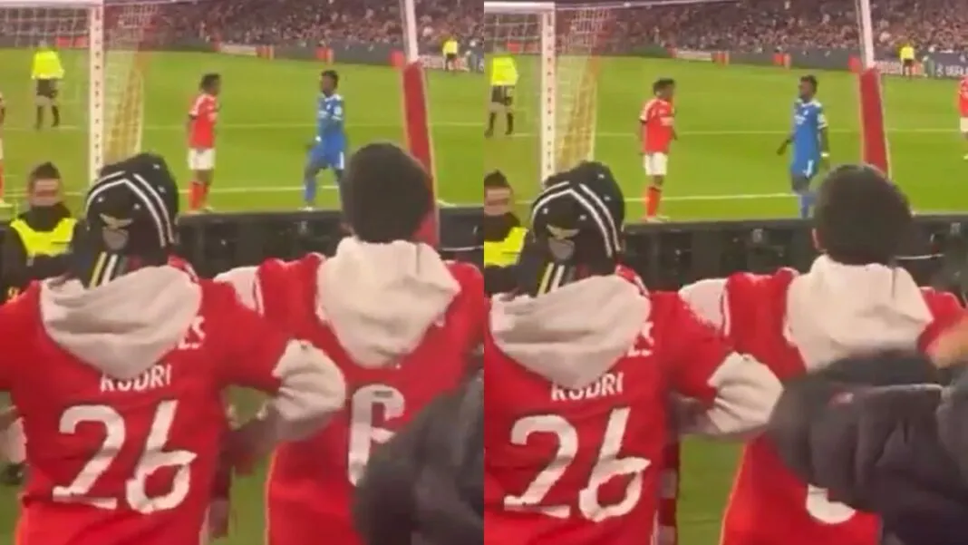 Montagem com duas imagens de baixa qualidade registradas da arquibancada de um estádio. Em primeiro plano, torcedores vestindo casacos vermelhos gesticulam em direção ao campo. No gramado, ao fundo, dois jogadores — um de uniforme vermelho e outro de azul — estão próximos.