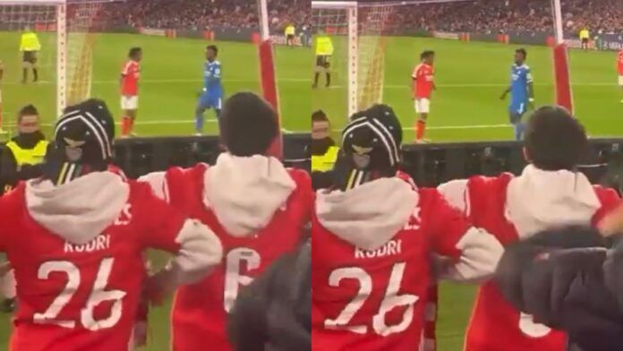 Montagem com duas imagens de baixa qualidade registradas da arquibancada de um estádio. Em primeiro plano, torcedores vestindo casacos vermelhos gesticulam em direção ao campo. No gramado, ao fundo, dois jogadores — um de uniforme vermelho e outro de azul — estão próximos.