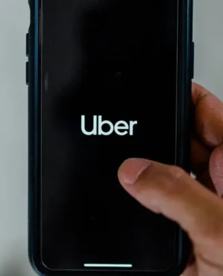 Uma mão mexe em um celular com o aplicativo da Uber na tela
