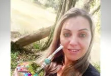 Roseli Vanda Pires Albuquerque tomando chimarrão em espaço público aberto, aparentemente um parque, perto de uma árvore